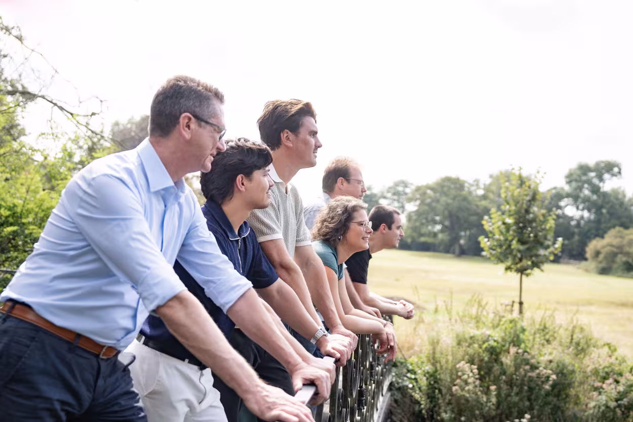 Medewerkers van Trivali staan op een brug, aan het kijken naar velden 